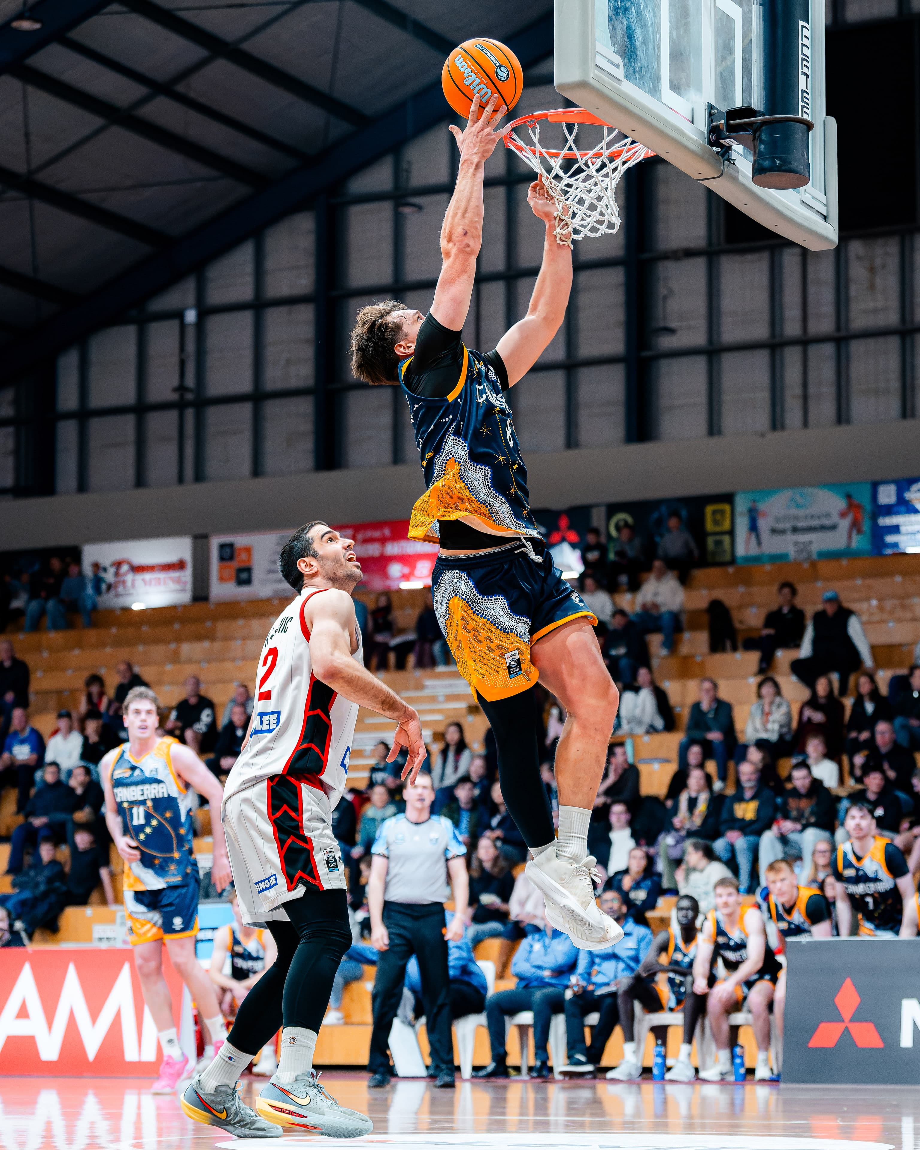 A Canberra Gunners player rises for a putback at the rim in front of a full grandstand