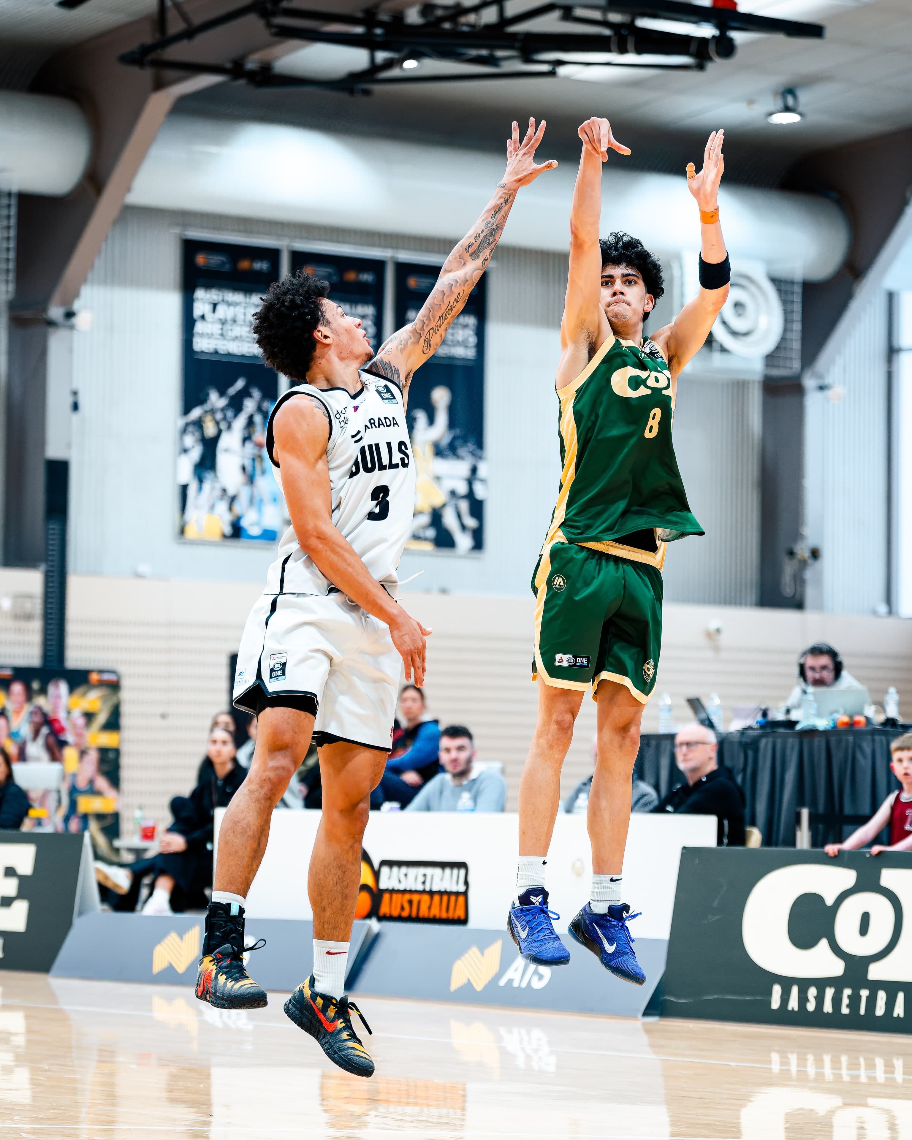 A COE shooter rises over a Bulls defender, both fully off the floor