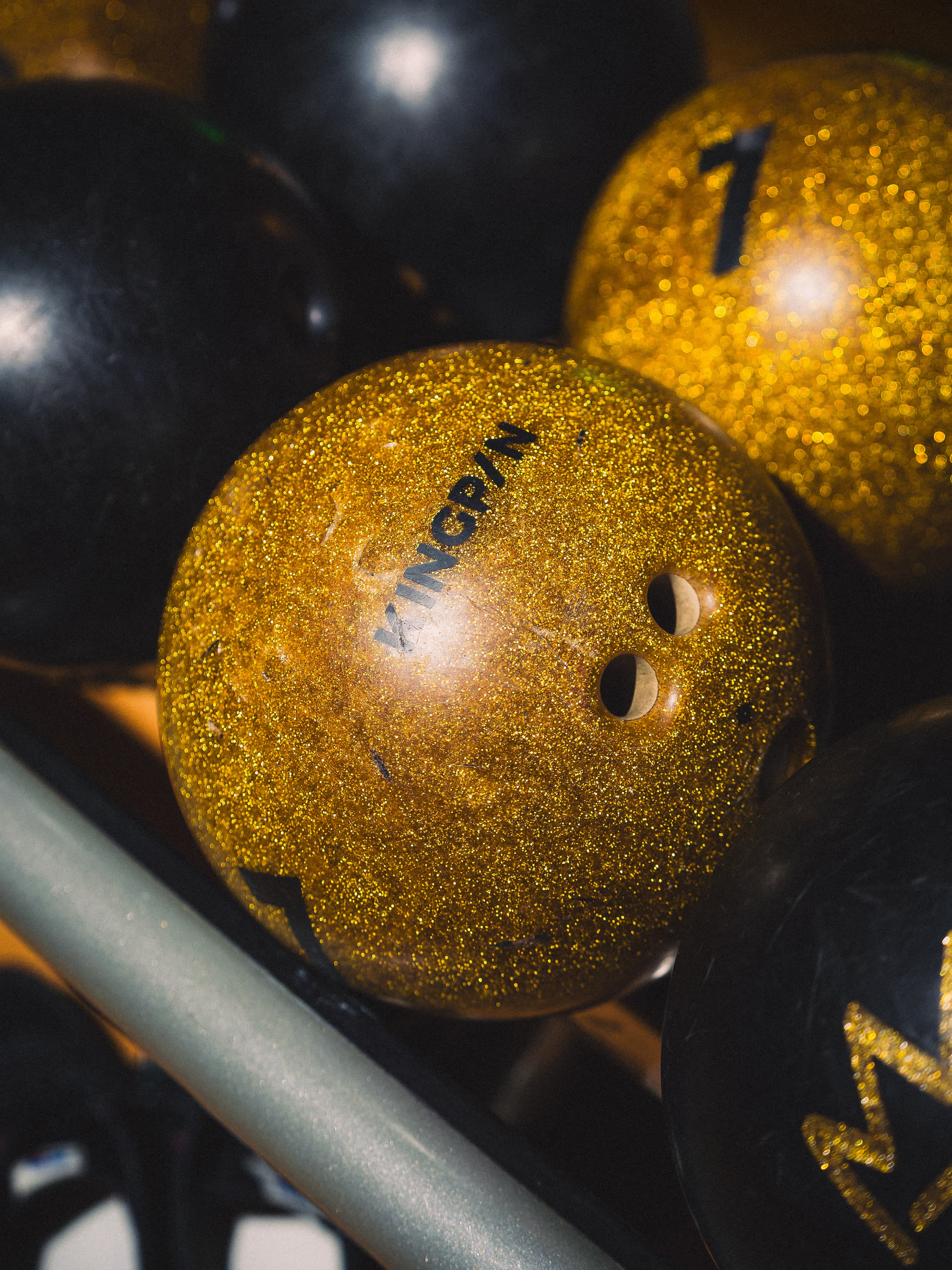 Close on a gold glitter bowling ball with the Kingpin name across it