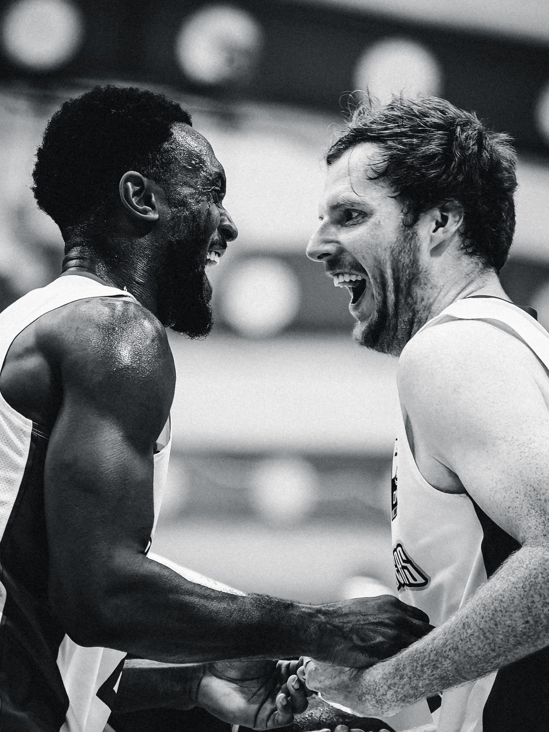 Two Central Coast Crusaders teammates grab each other and roar after a score, in black and white