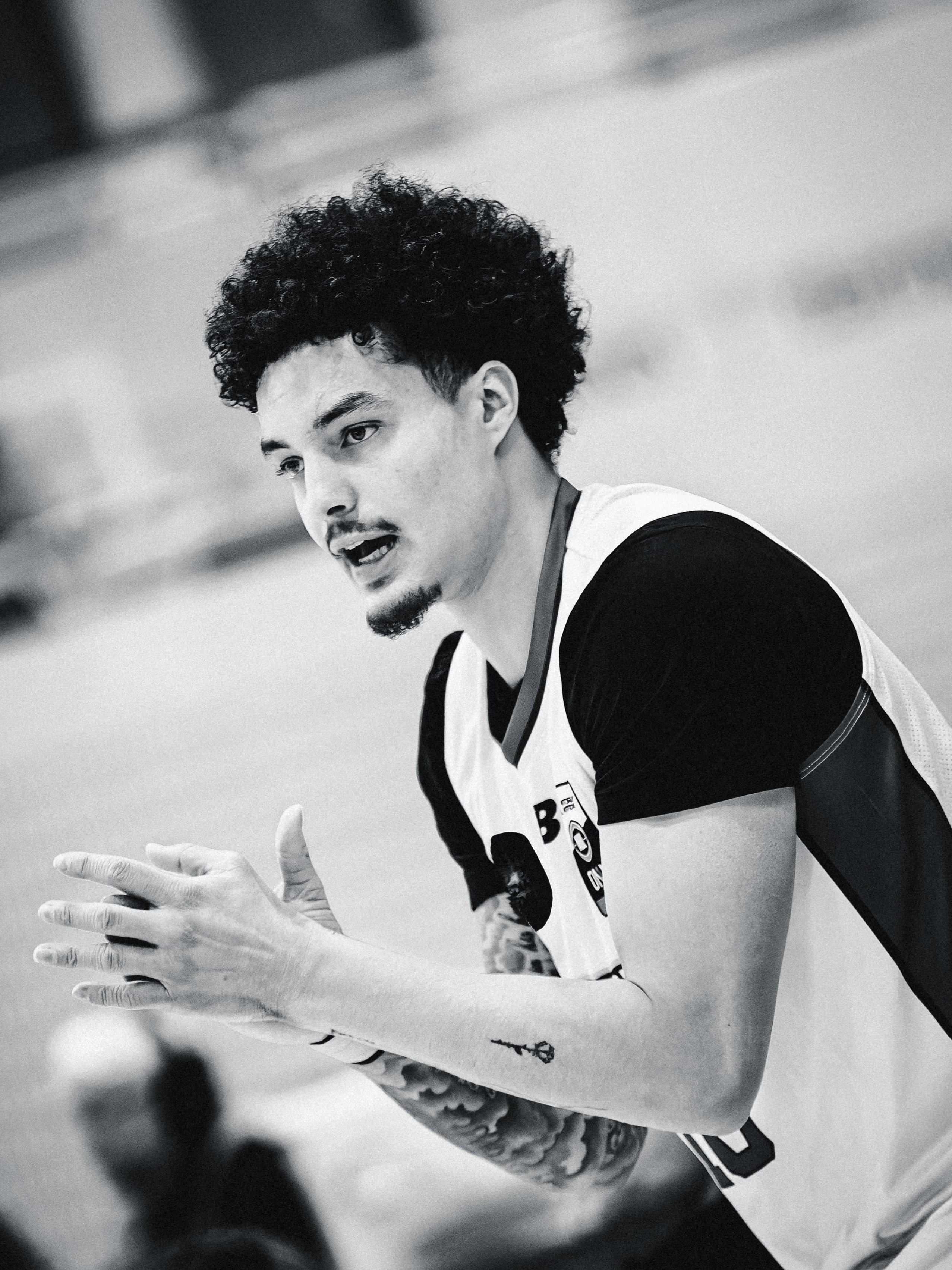 A player claps and calls to a teammate mid game, in black and white