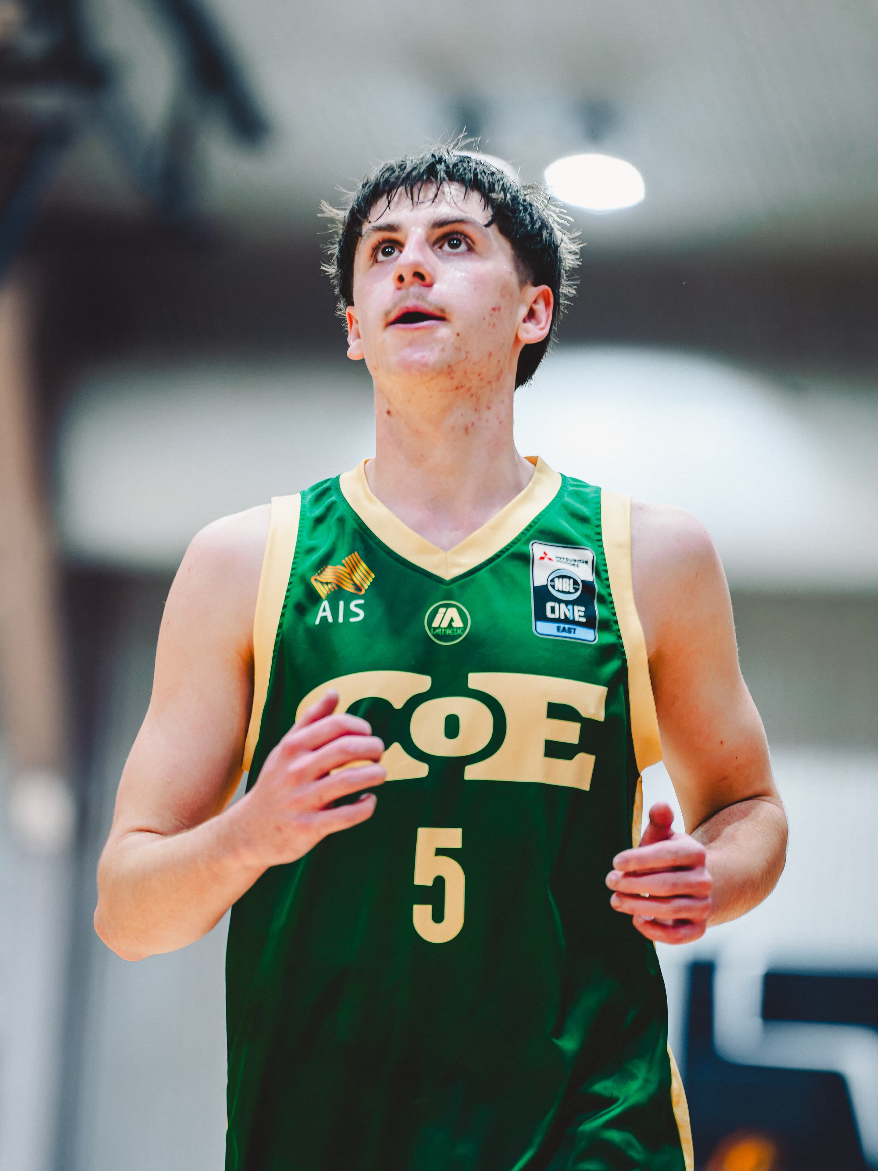 A Centre of Excellence player looks up the court between plays in the green kit