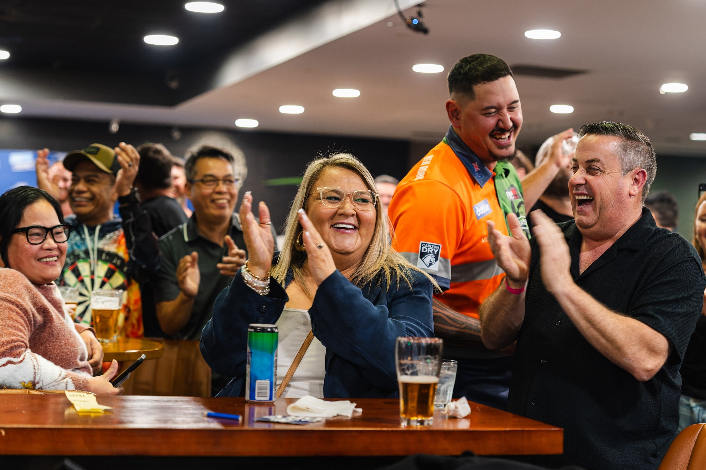 Guests react together around a table during the darts event