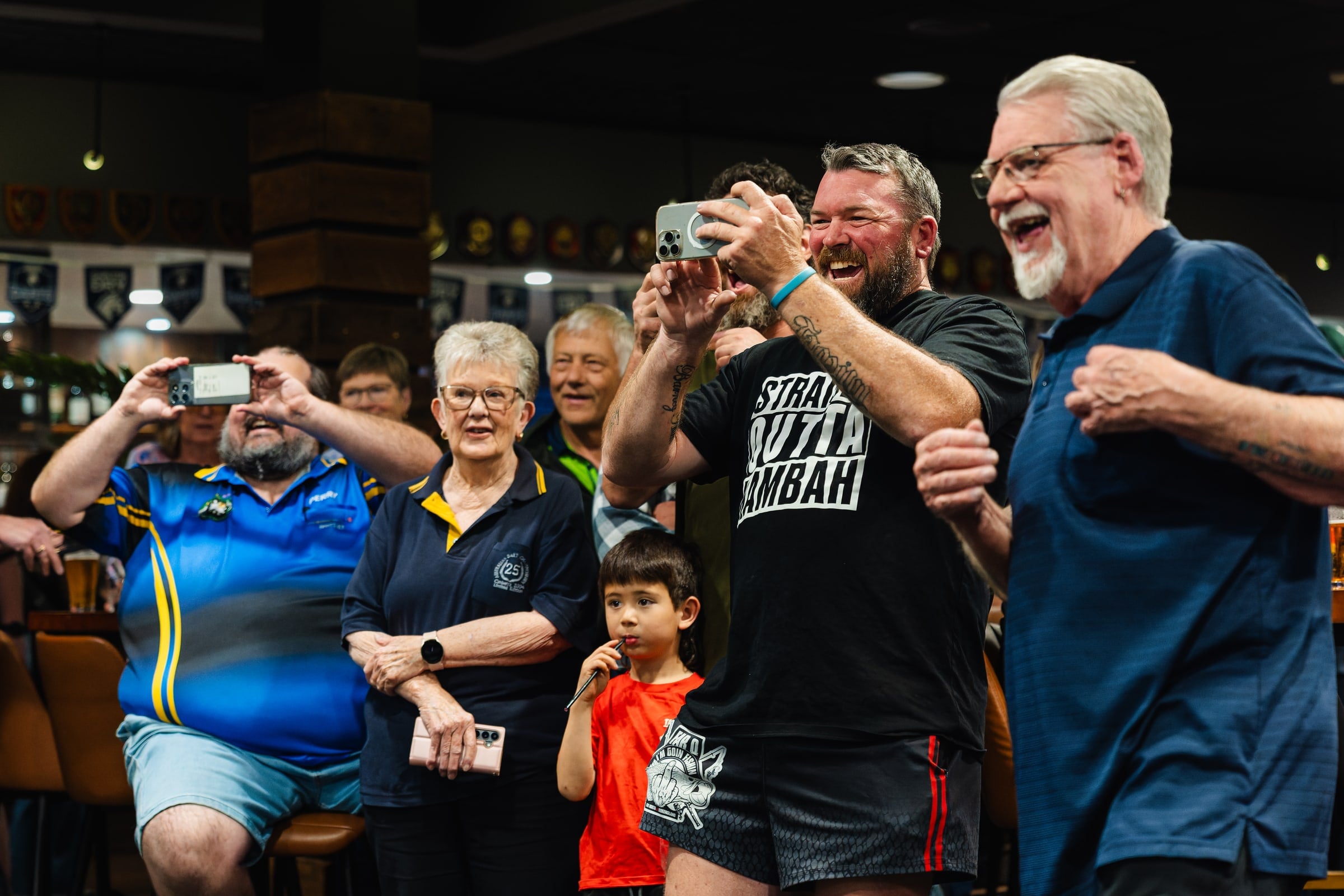 Guests cheer beside the dartboard with drinks in hand