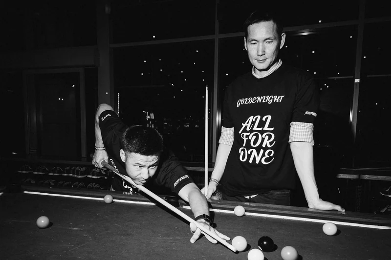 Black and white photograph of two guests playing pool