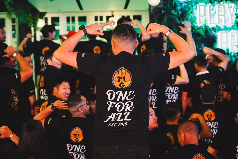 Anniversary guests raising their arms with a One For All shirt in the foreground