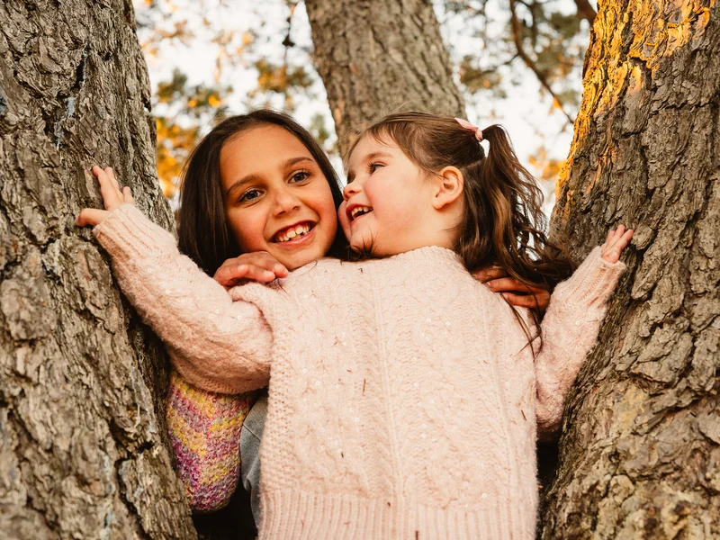 Two children laughing together between branches of a tree