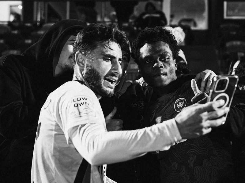 Black and white photograph of a football player taking a selfie with a fan