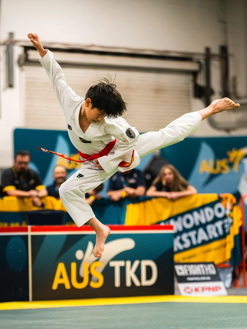 A Taekwondo athlete airborne with one leg extended to the side