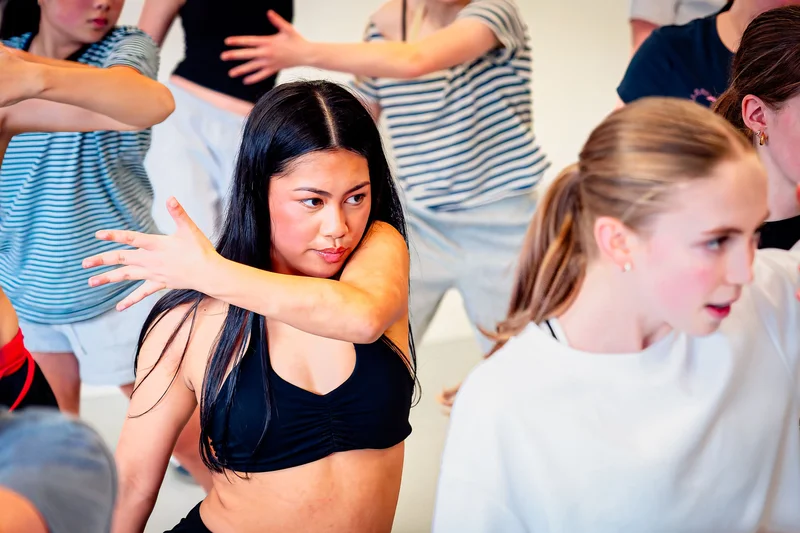 A dancer with her arms extended during a studio class