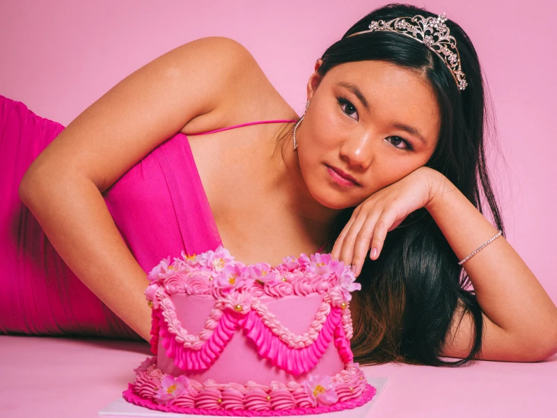 Portrait in pink beside a decorated heart-shaped cake