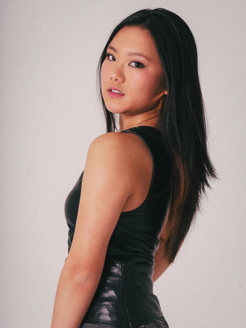 Looking back over one shoulder against a pale studio backdrop