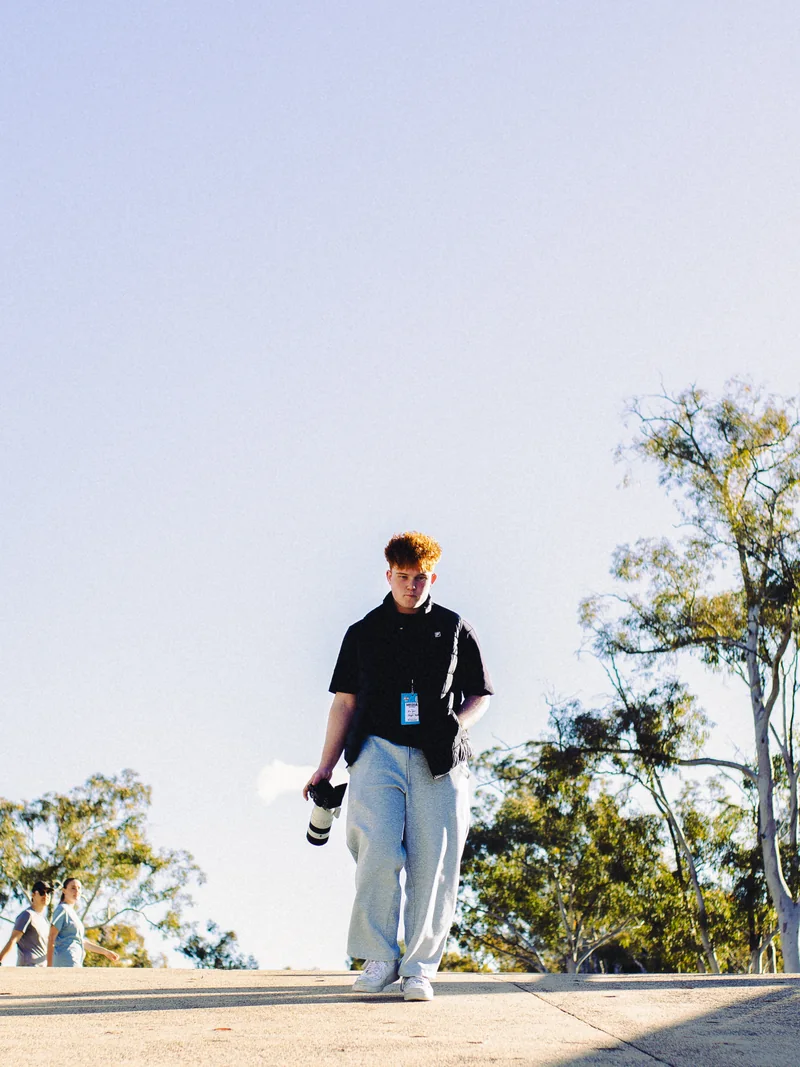 Kian walking outdoors with a camera in hand