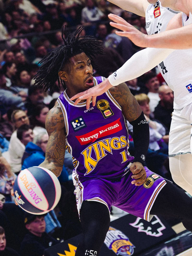 Sydney Kings player dribbling past a New Zealand Breakers defender