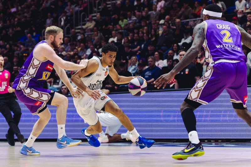 New Zealand Breakers player driving between two Sydney Kings defenders