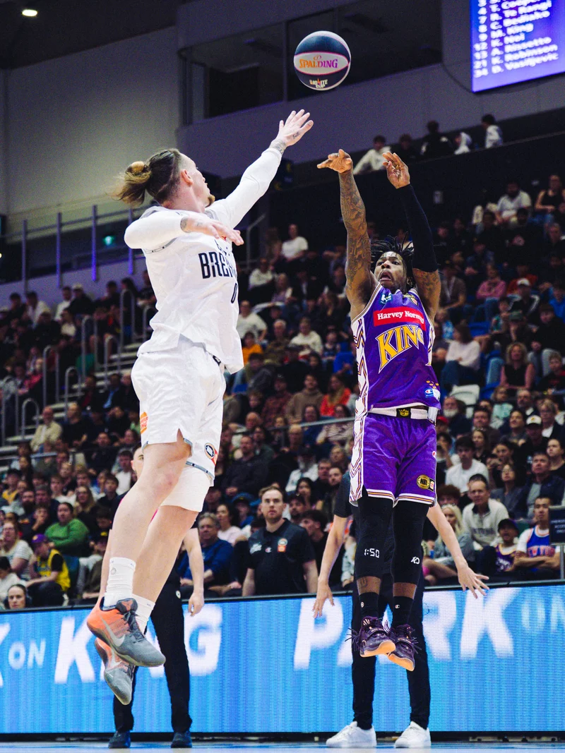 Sydney Kings player releasing a jump shot over a New Zealand Breakers defender