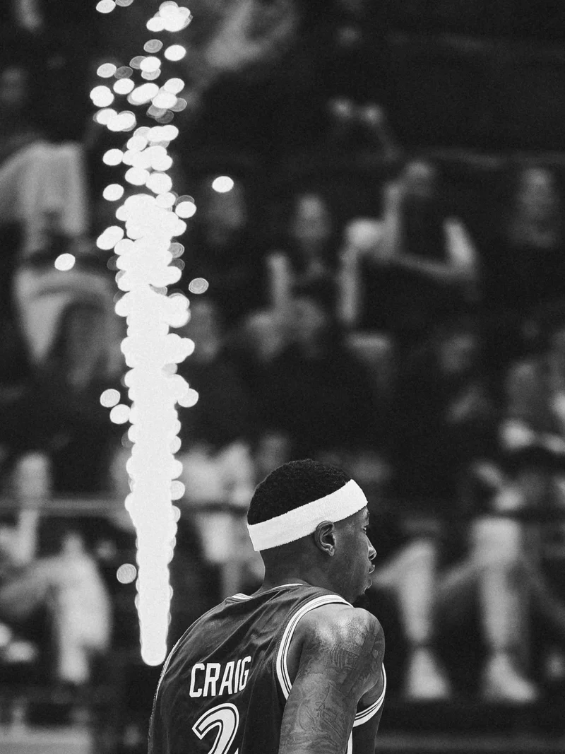 Black and white photograph of a Sydney Kings player with sparks rising behind him